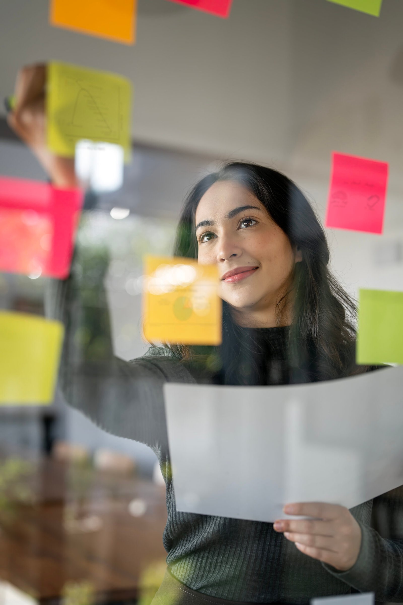 young smiley attractive, businesswoman using sticky notes in gla