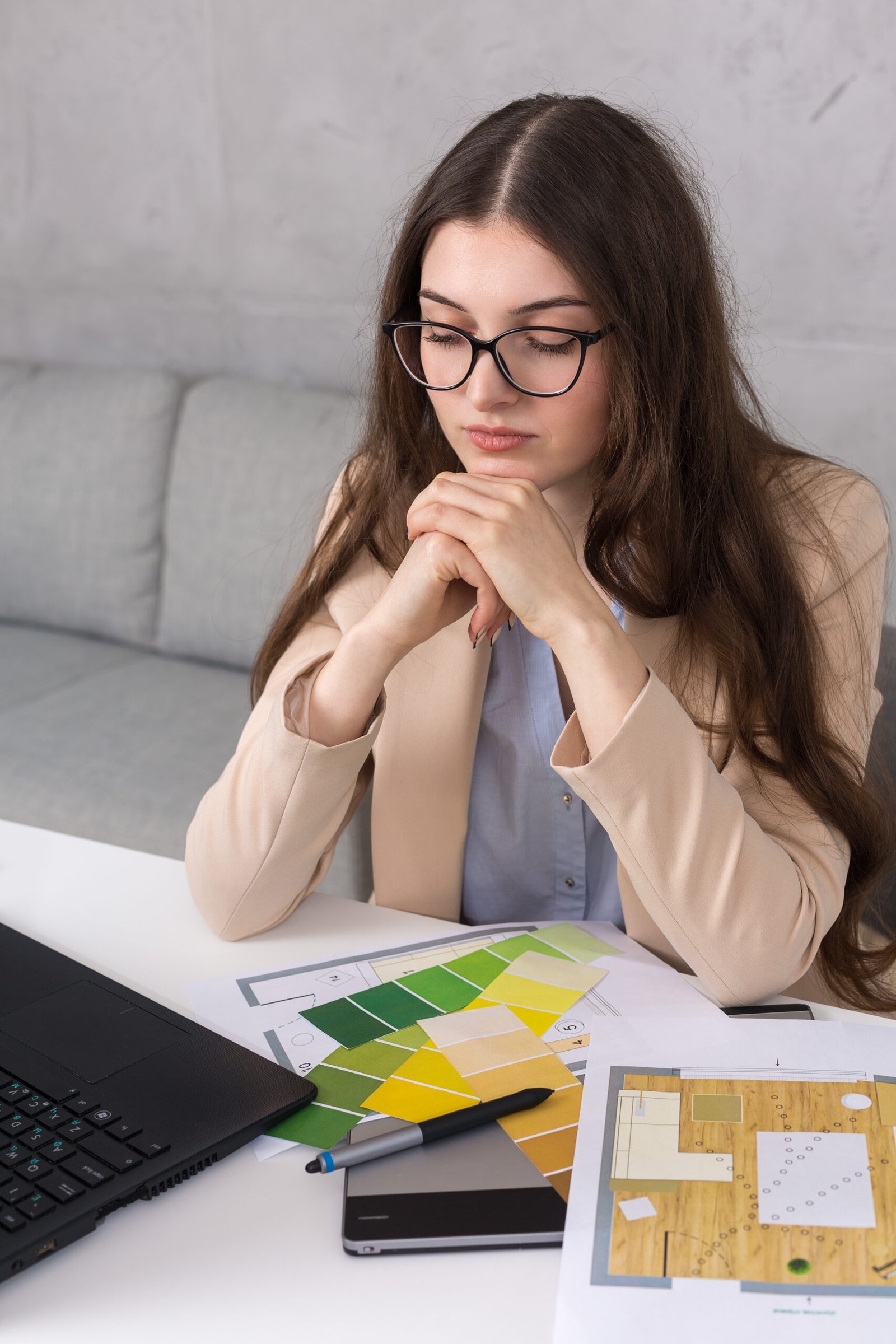a young designer girl sitting at a table draws on a tablet. makes business calculations on the computer.